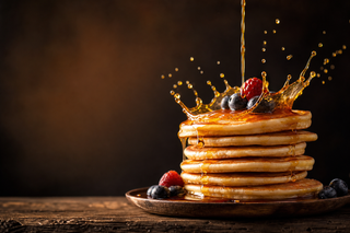 Bánh pancake phủ siro với quả mọng trên bàn gỗ