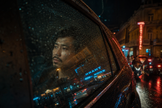 Người đàn ông trong xe dưới mưa đêm thành thị