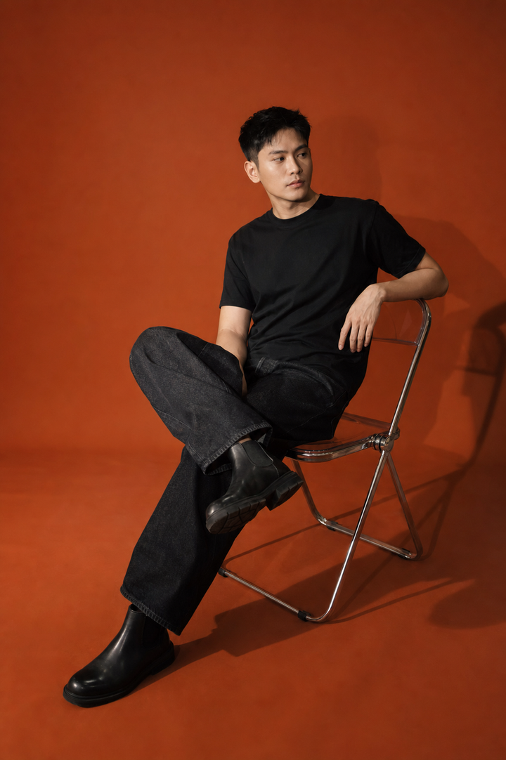 Chân dung nam ngồi ghế gấp trên nền cam studio